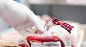 Scientist's hand holding a red blood bag in storage blood refrigerator at blood bank unit laboratory